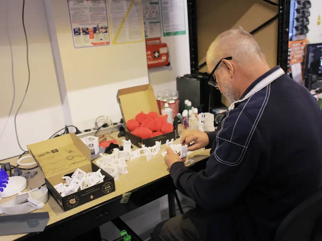 Stanowisko w drukarni 3D do mechanicznej obróbki i usuwania podpór z wydruków - technik podczas pracy